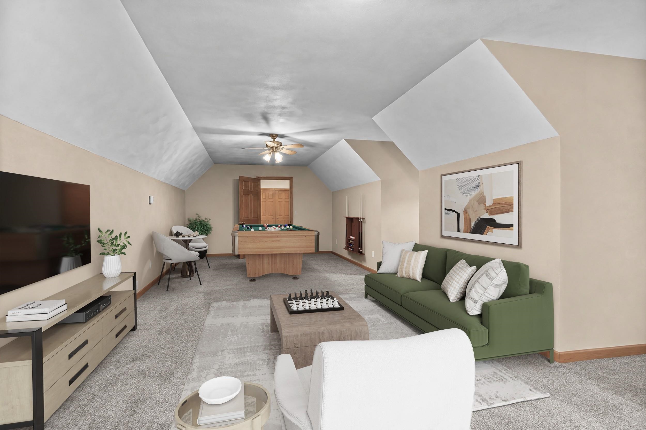 Staged recreation room with a pool table, green sofa, and vaulted ceiling.