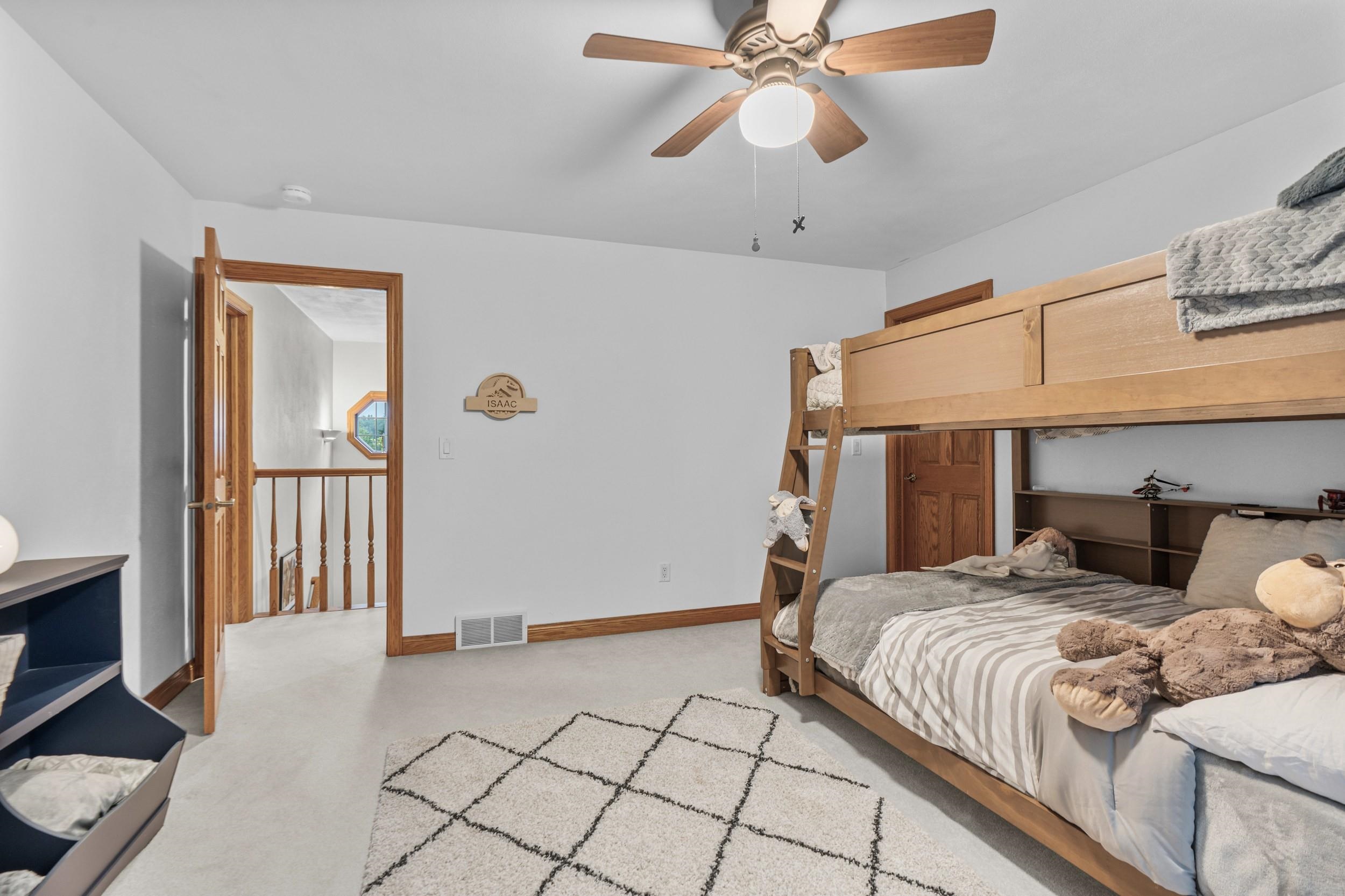 Bedroom with a wooden bunk bed, gray-and-white bedding, and an open doorway to the landing.