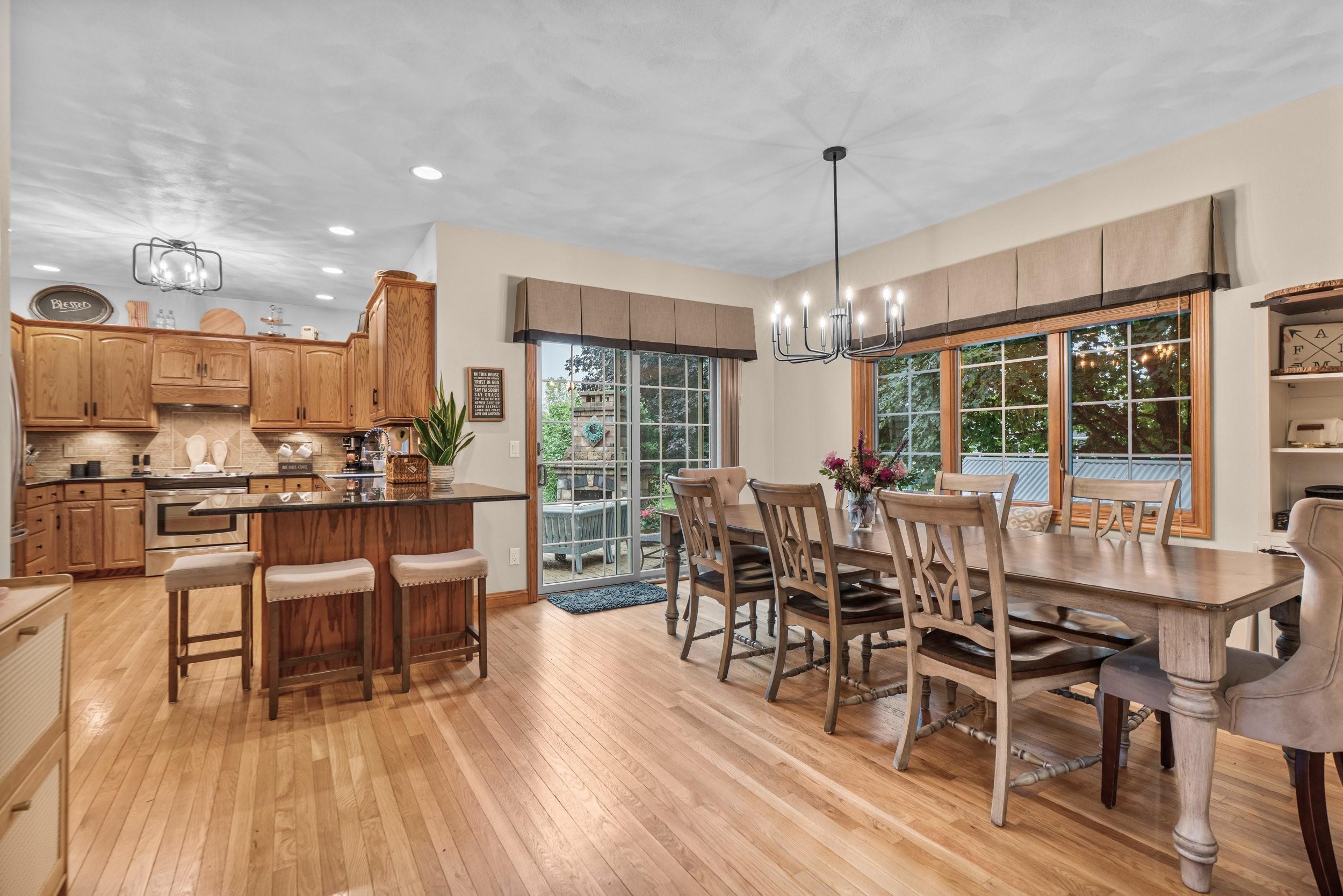 Kitchen and dining area with a wood island, long dining table, hardwood floors, and large windows.