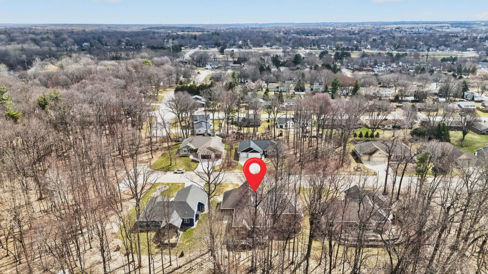 Aerial neighborhood view with a red map pin marking 448 Harvest Road among leafless trees.
