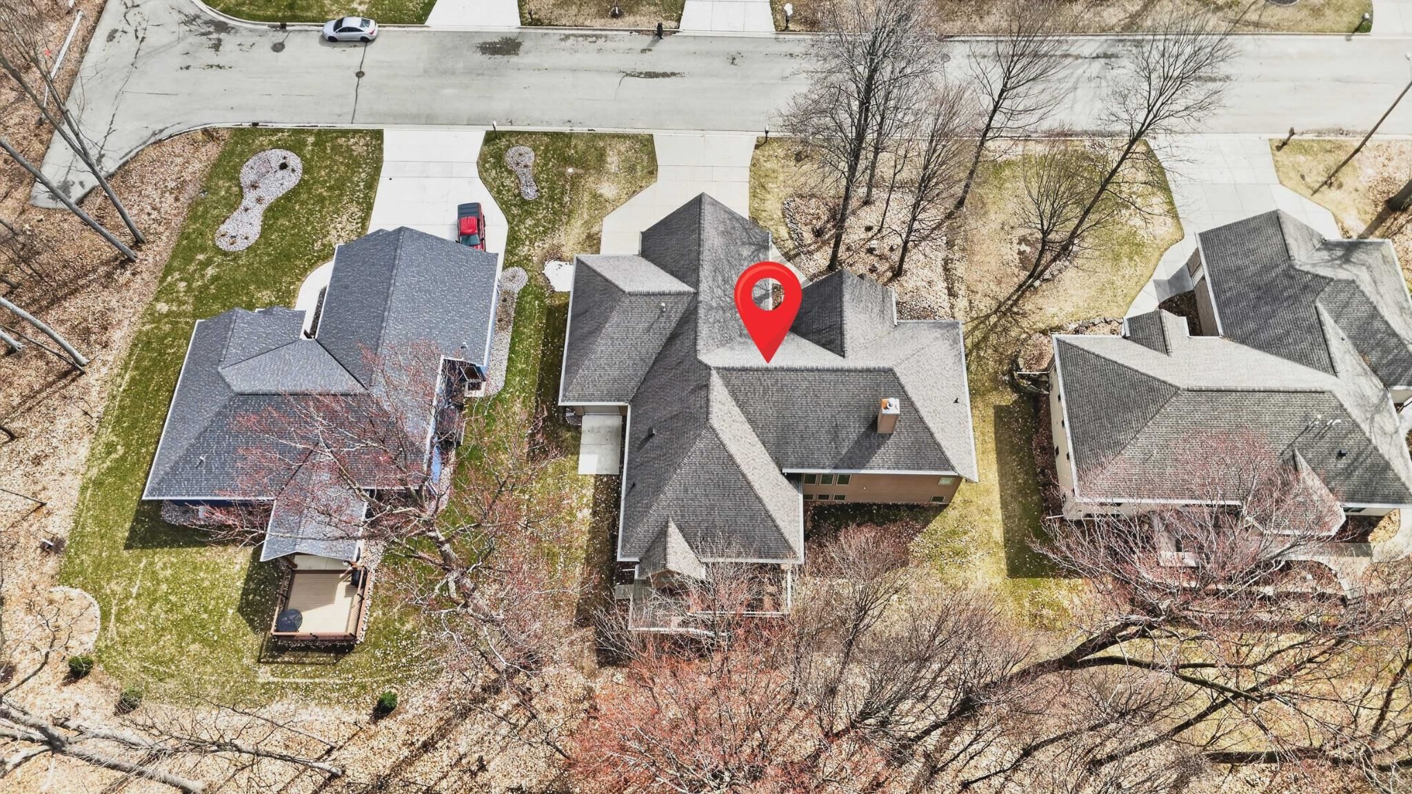 Aerial view of a house marked by a red pin, with neighboring homes and a residential street.