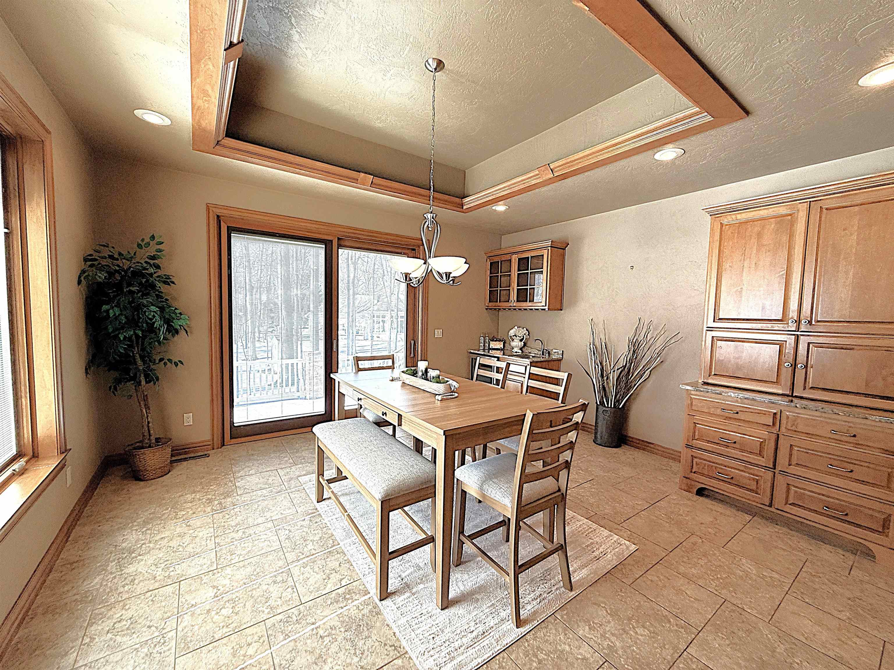 Dining room with a wooden table, built-in cabinetry, tray ceiling, and sliding glass doors to a deck.