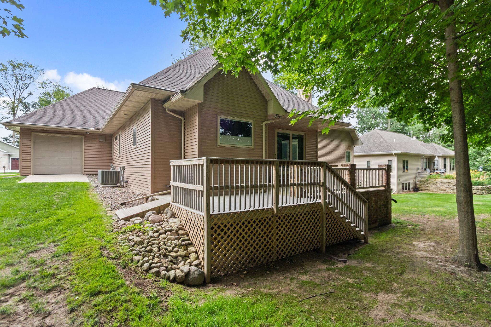 House exterior with a raised wooden deck, lattice skirting, and attached garage.