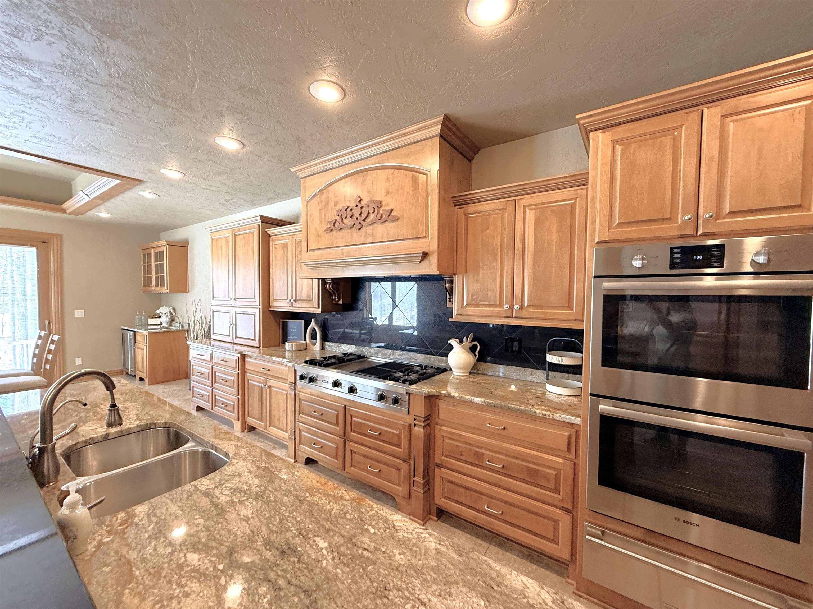 Kitchen with warm wood cabinetry, granite counters, a gas cooktop, and stainless steel double wall ovens.