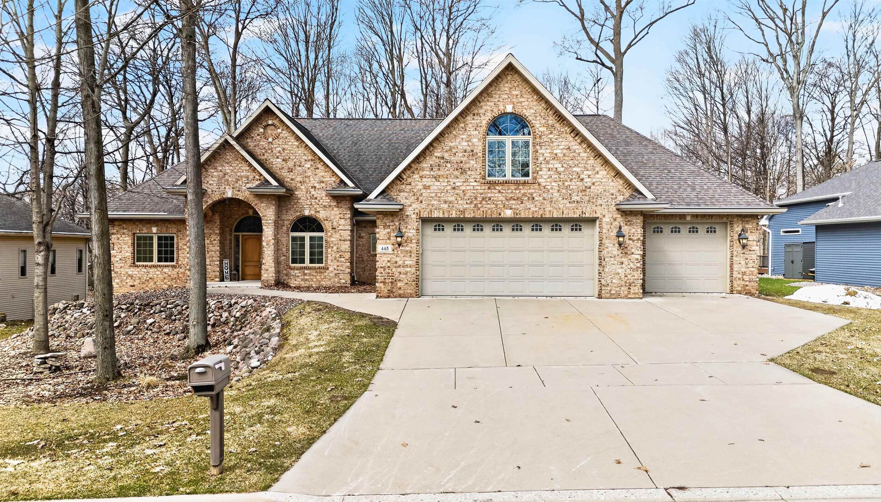 Brick house with multiple gables, an arched entryway, and a three-car garage.