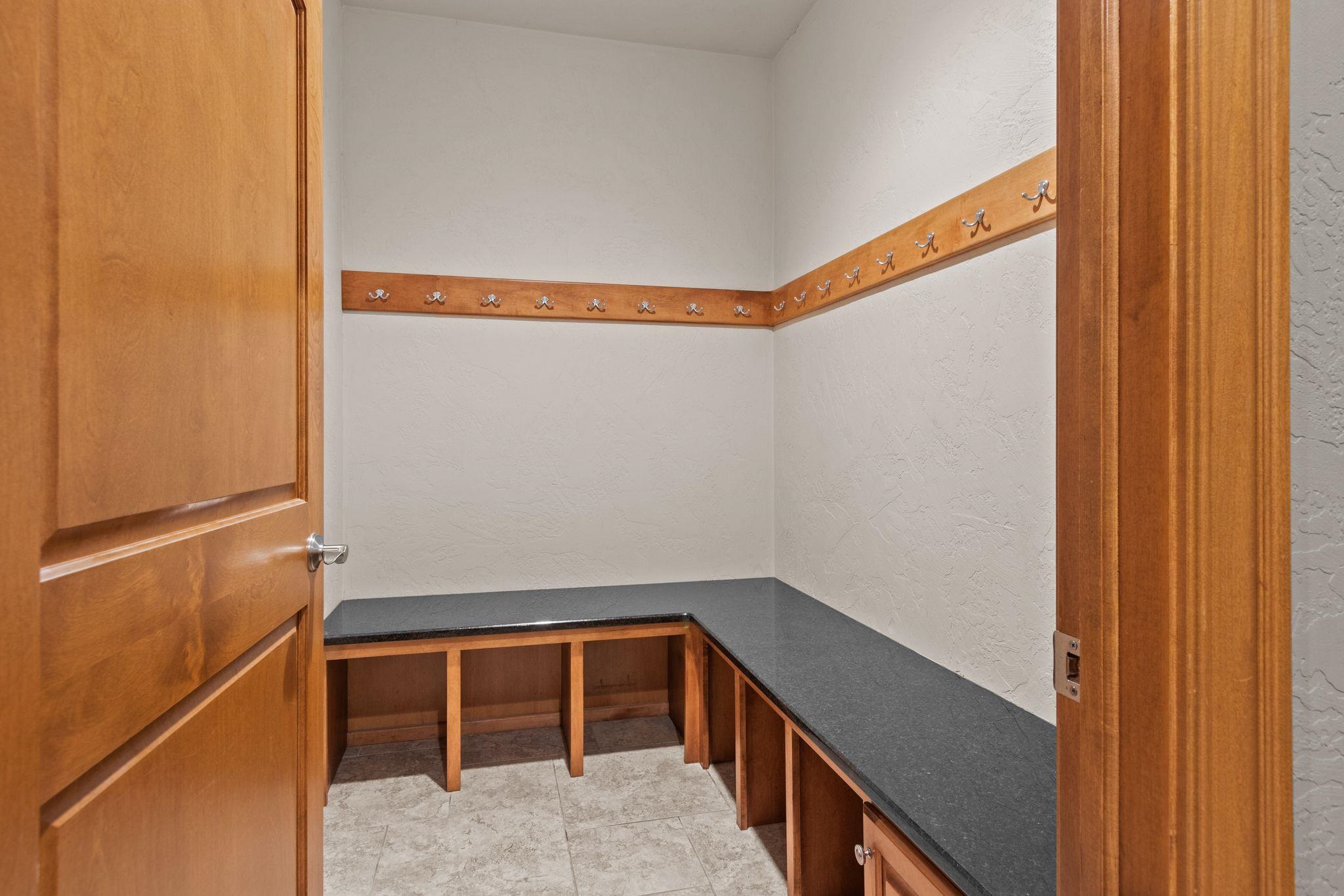 Walk-in closet with wall hooks, L-shaped counter, and built-in wooden cubbies.