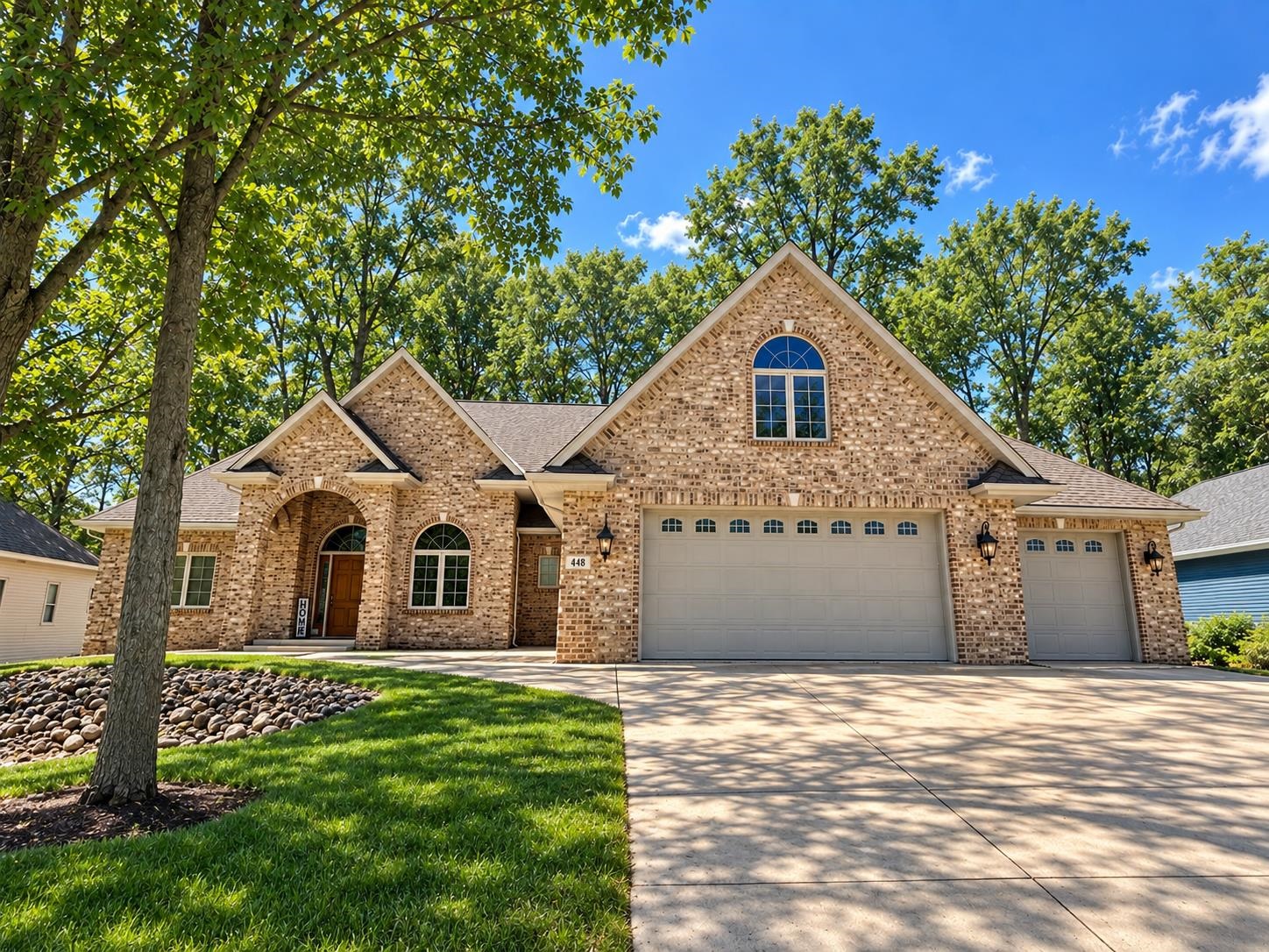 Tan brick home with peaked gables, an arched entry, and a three-car garage.