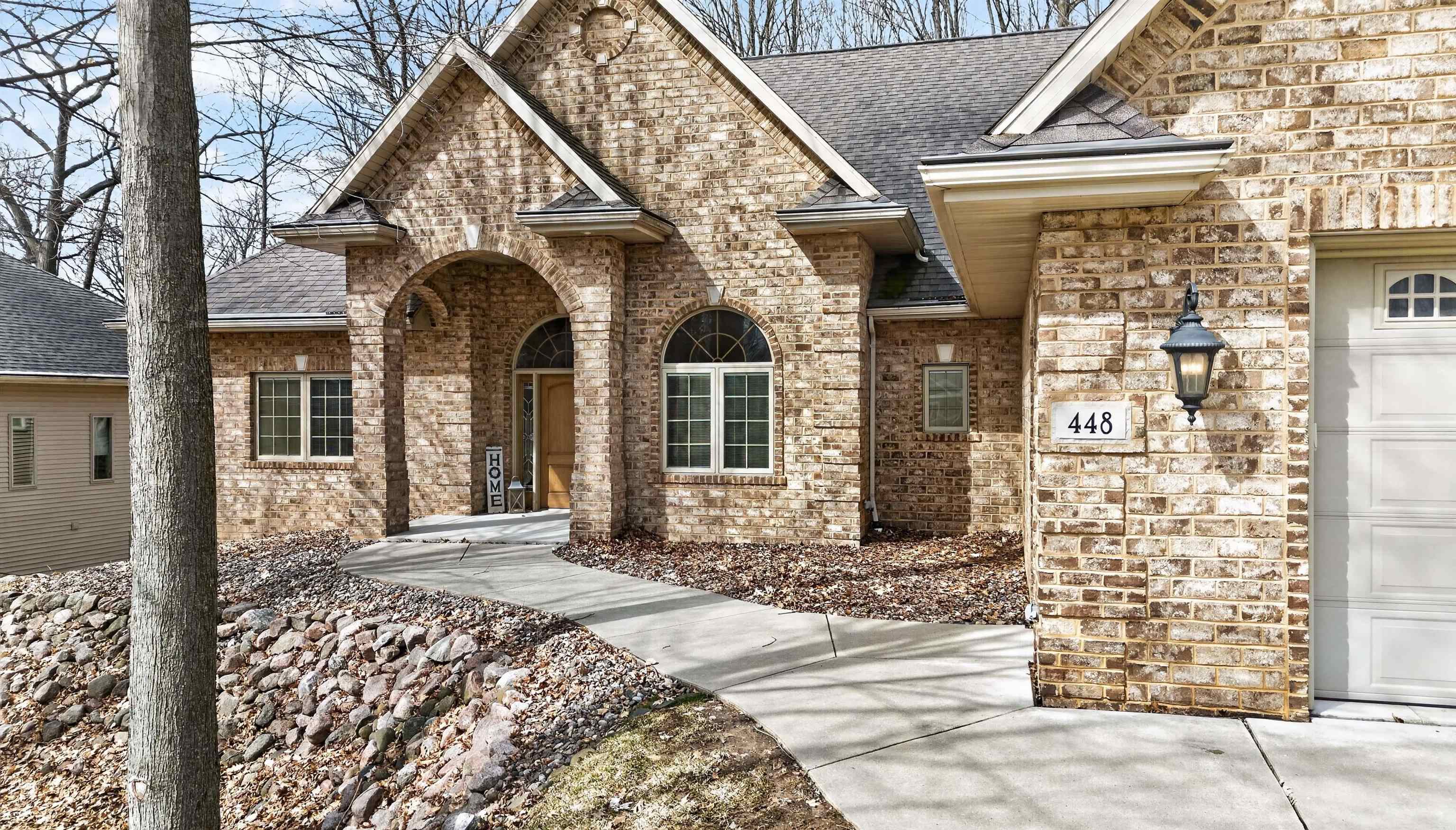 Brick house with an arched entry, curved walkway, and number 448 beside the garage.