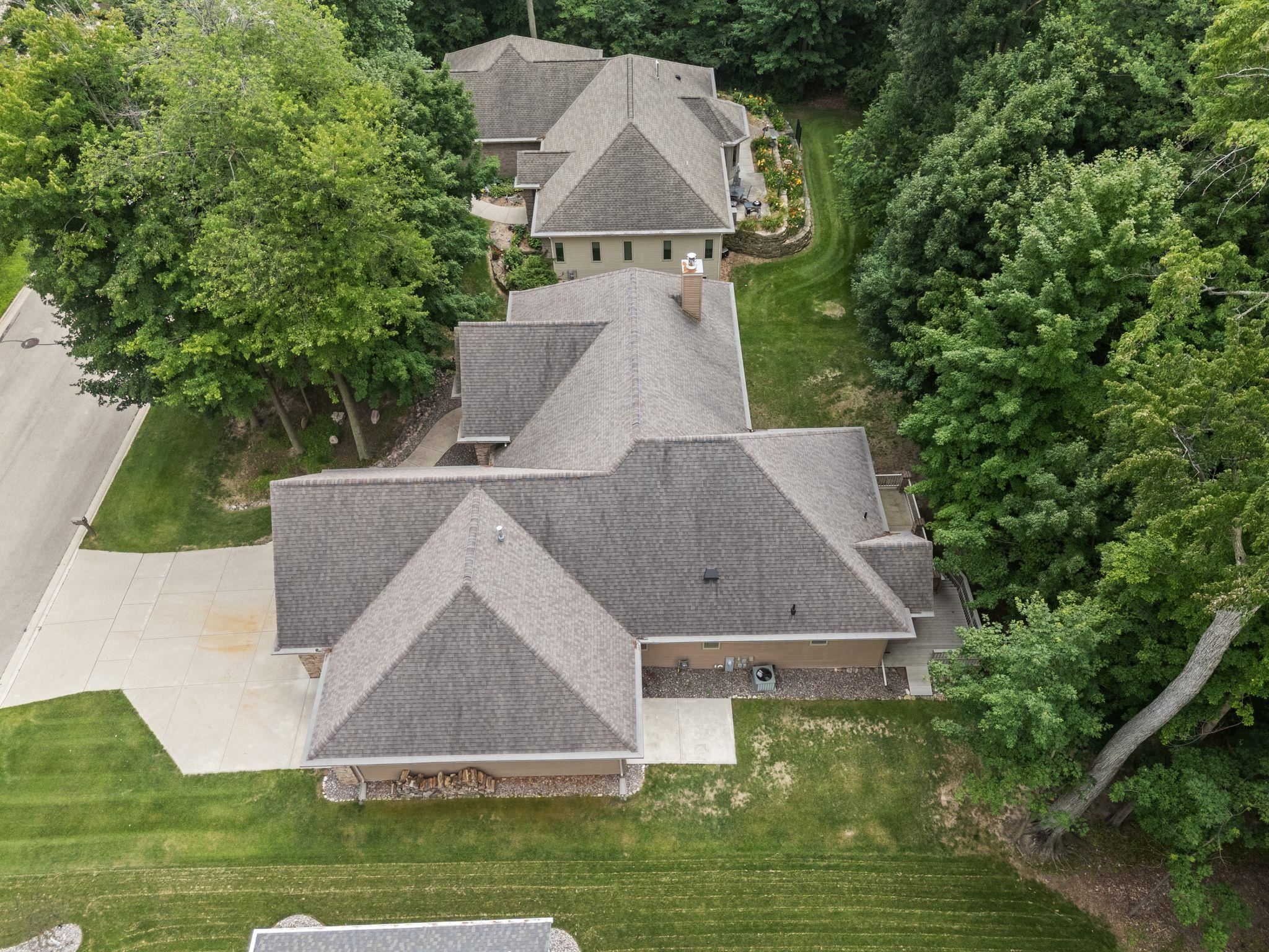 Aerial view of a house with a broad driveway and mature trees.