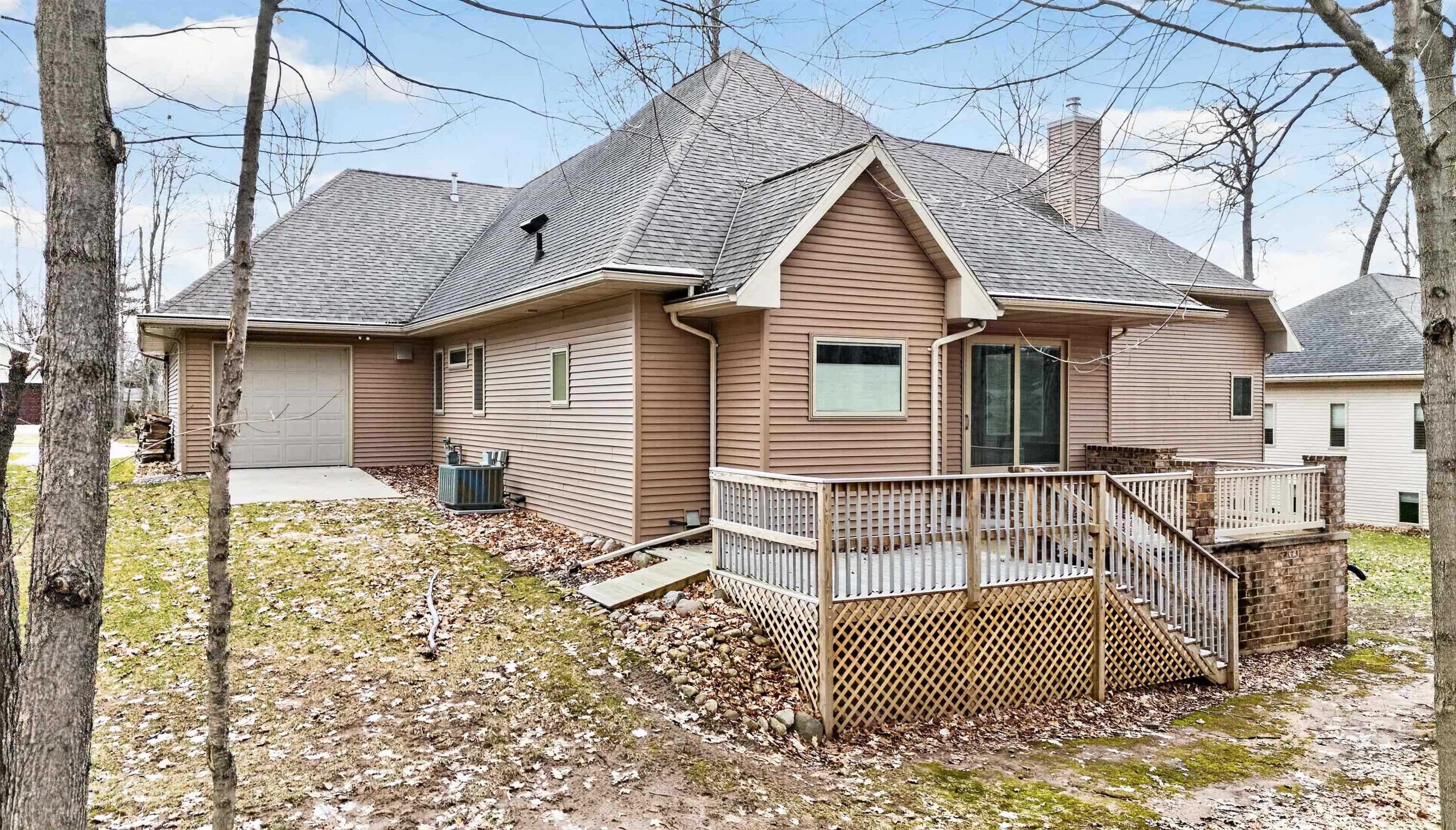 Rear of a tan-sided house with an attached garage and raised deck.