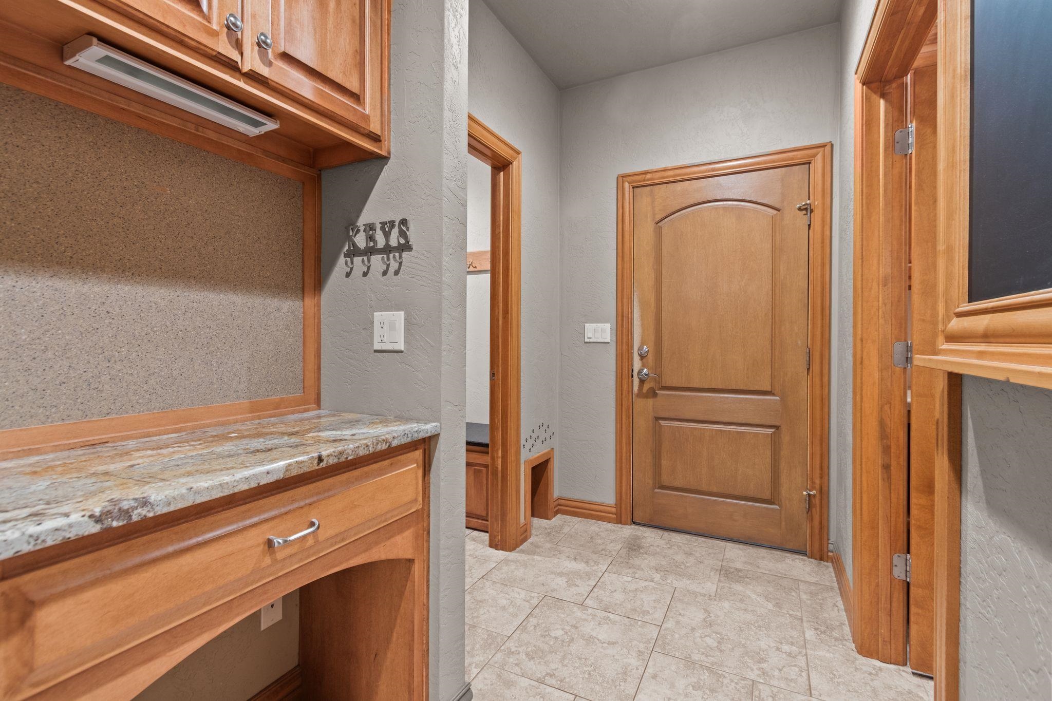 Entryway with a wood front door, tiled floor, and built-in counter with a key rack.