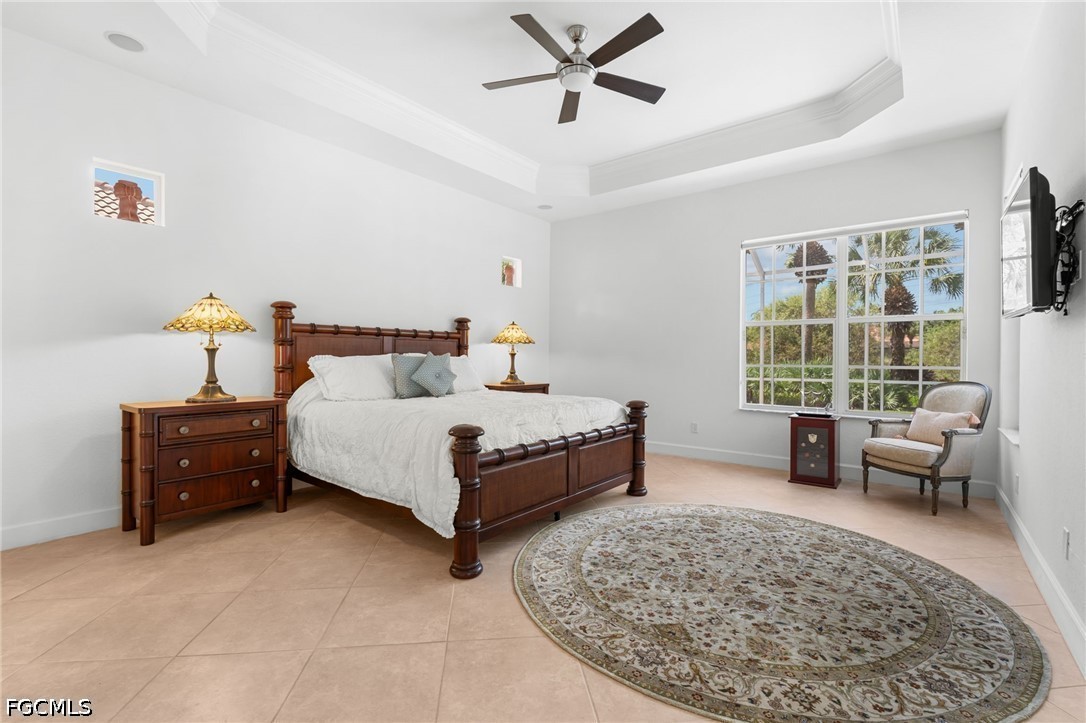 Bedroom with a dark wood four-poster bed, tray ceiling, and large window overlooking palm trees.