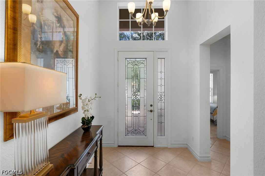 Furnished entry foyer with decorative glass front door, chandelier, and dark wood console table.