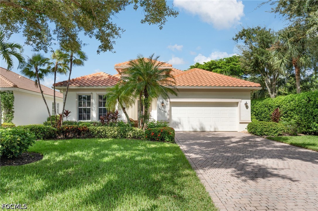 Single-story home with a terracotta tile roof, paver driveway, and palm-lined lawn.