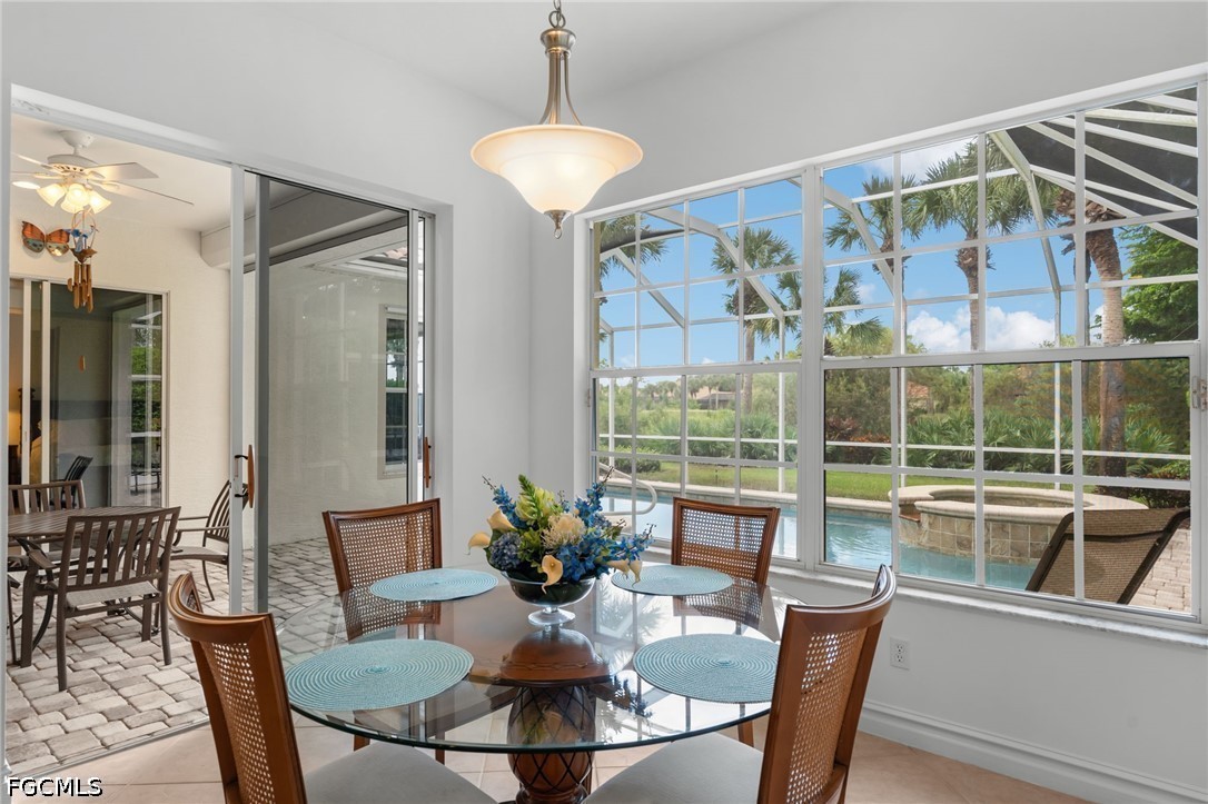 Dining area with a round glass table overlooking a pool and palm-lined patio.