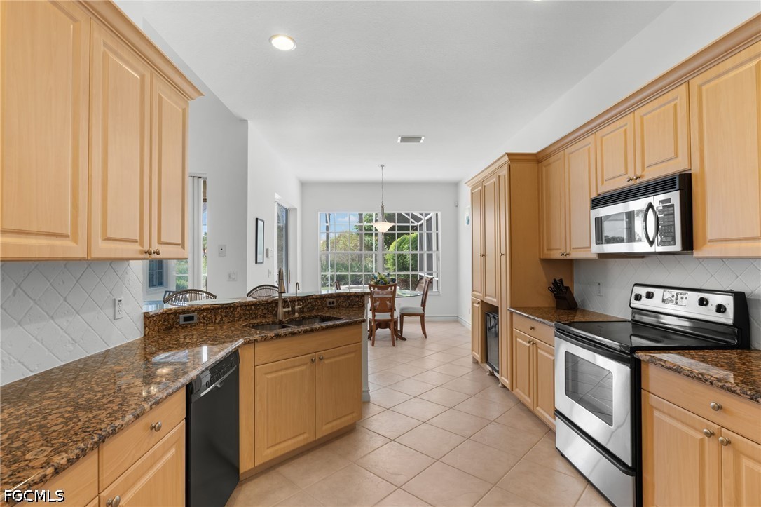 Kitchen with honey-colored cabinets, granite counters, a central island, and stainless steel appliances.