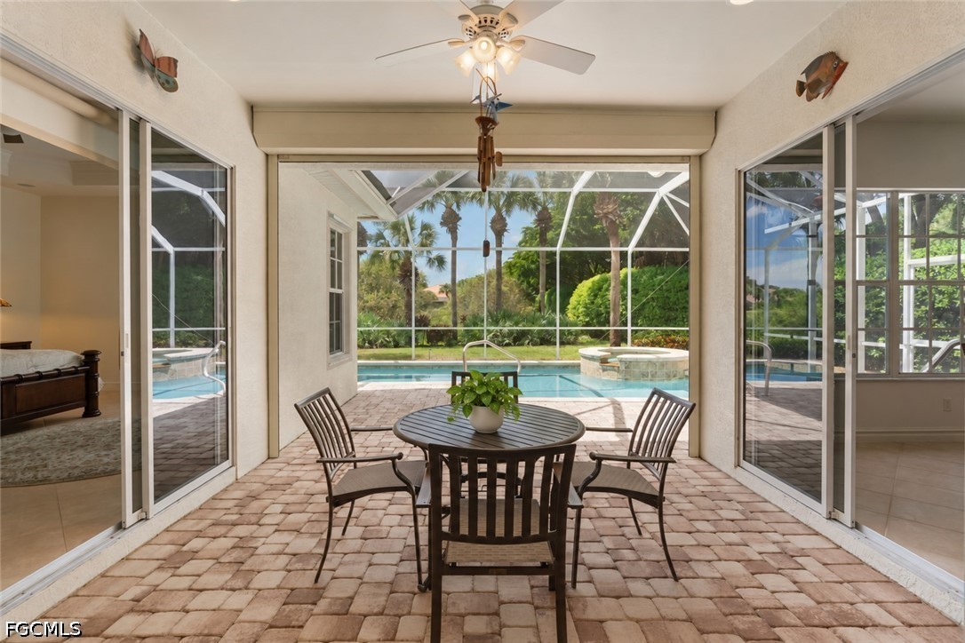 Screened lanai with a round dining set overlooking a pool and raised spa.