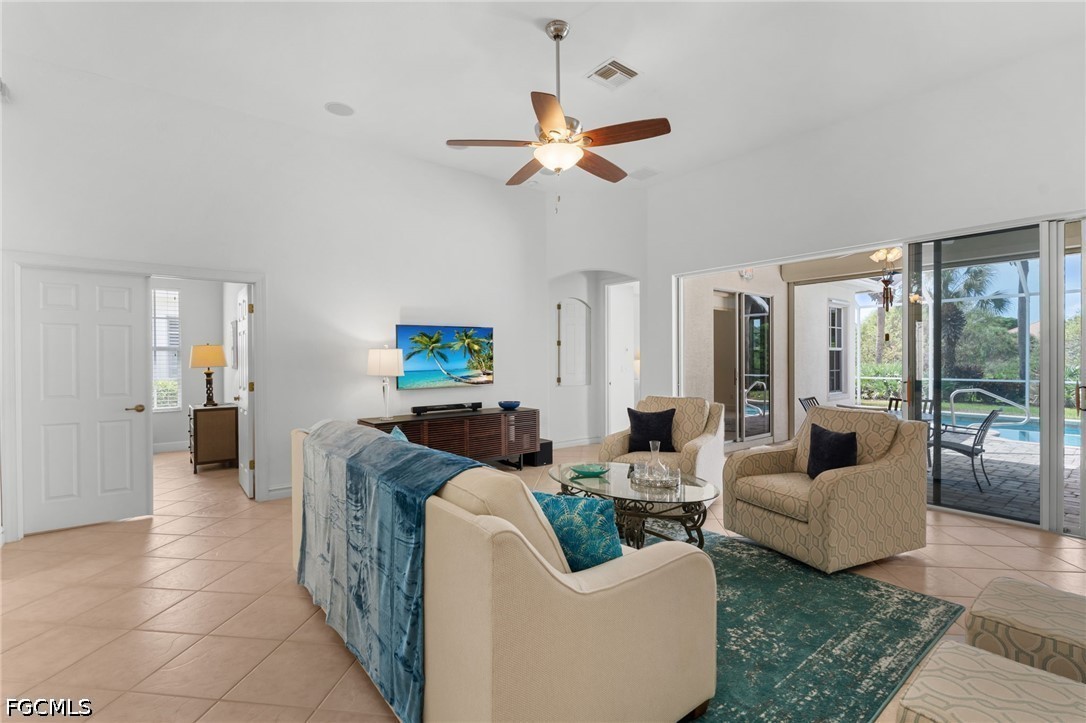Living room with beige seating and teal rug, opening through sliding glass doors to a pool patio.