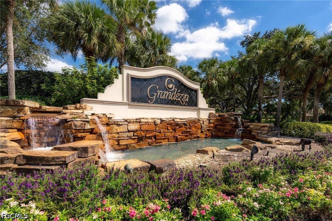Grandézza entrance sign above a stone waterfall and landscaped flower beds.