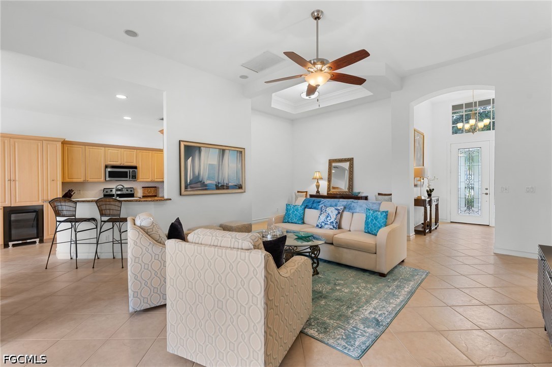 Furnished living room with a tray ceiling and ceiling fan, open to a kitchen with a breakfast bar.