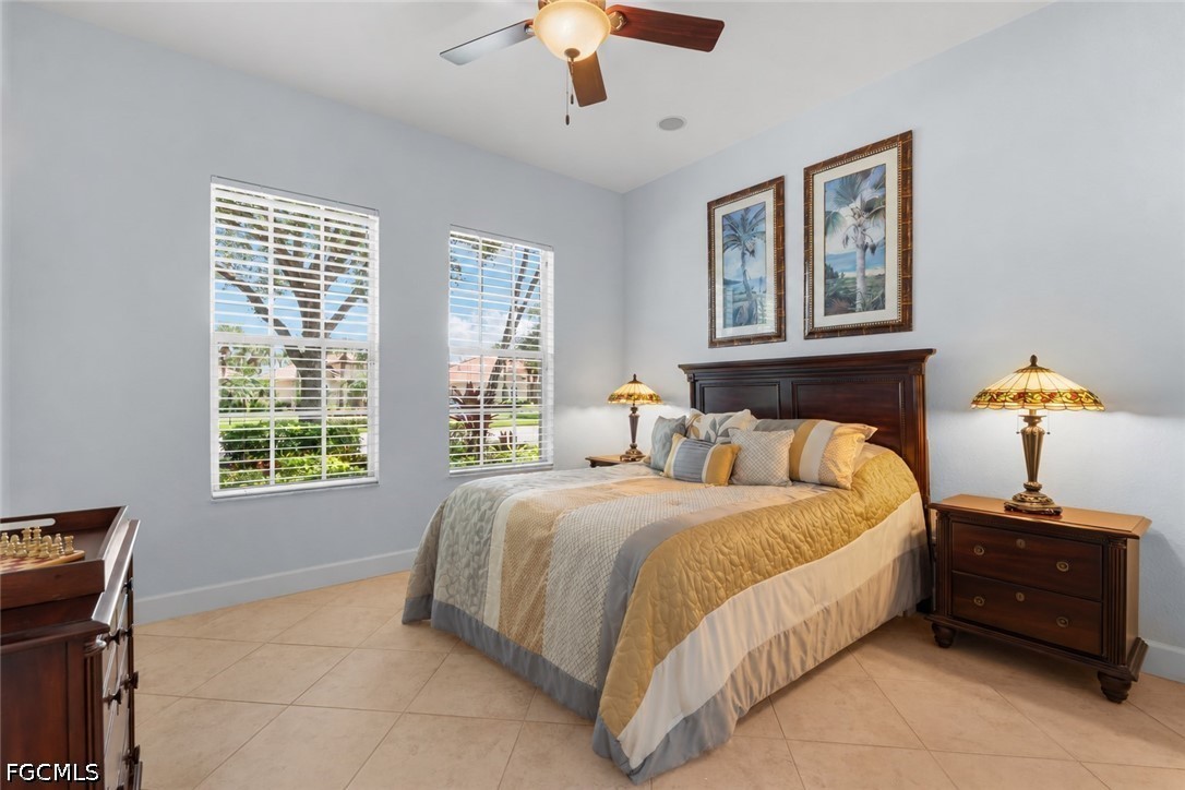 Bedroom with a king bed, dark wood furniture, palm-tree artwork, and two shuttered windows.