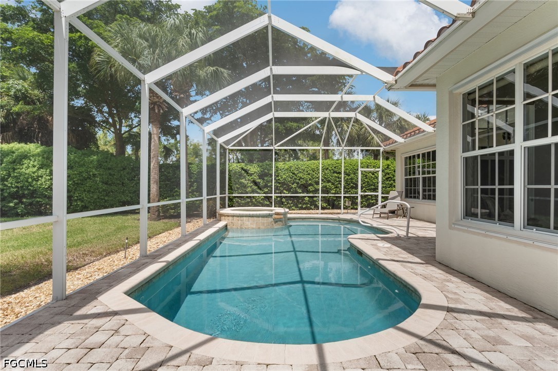 Screened backyard pool with a raised spa and paver deck.