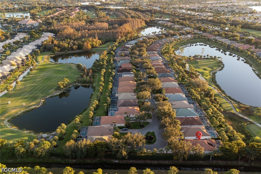 Aerial view of homes beside golf course ponds and fairways, with a red marker on one home.