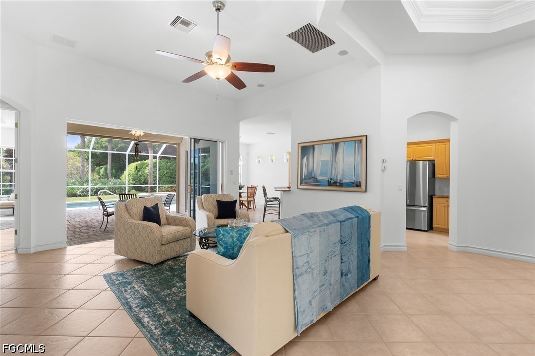 Living room with beige seating and blue accents, opening through sliding doors to a patio and pool.