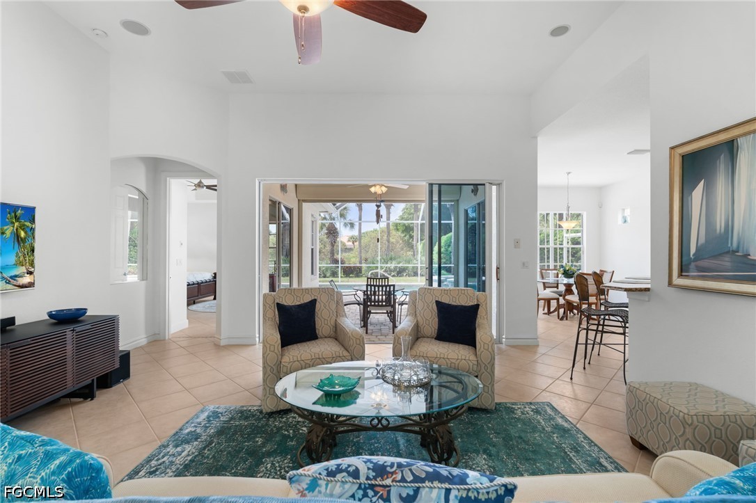 Furnished living room with teal rug, glass coffee table, and sliding doors to a screened outdoor area.