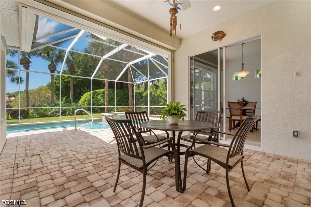 Screened poolside patio with a round dining table and tropical landscaping.