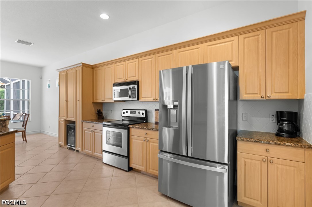Kitchen with honey-colored cabinets, granite counters, and stainless steel appliances.