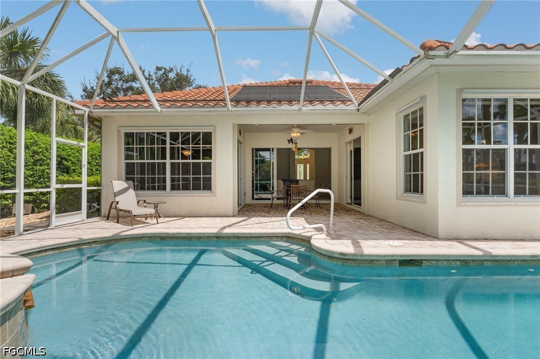 Swimming pool beneath a screened patio beside the home, with paver decking and lounge chairs.