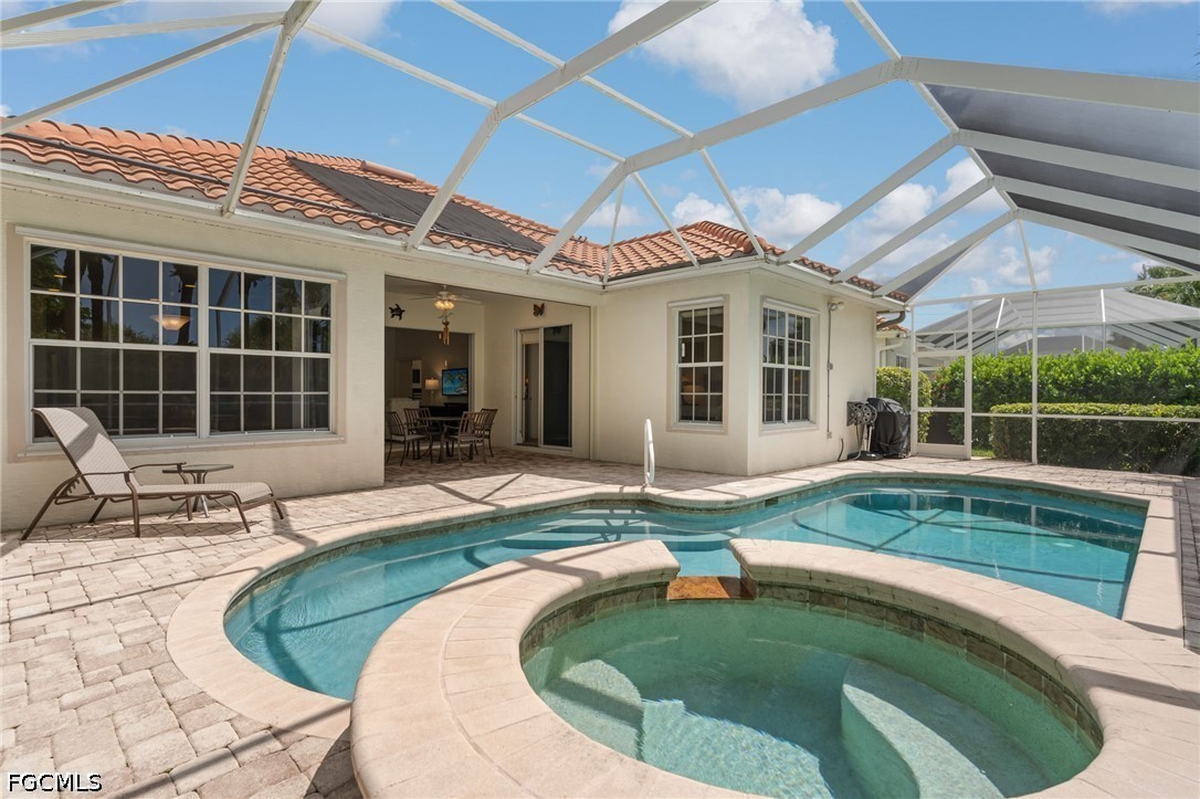 Screened lanai with a swimming pool, raised circular spa, and paved patio beside the house.