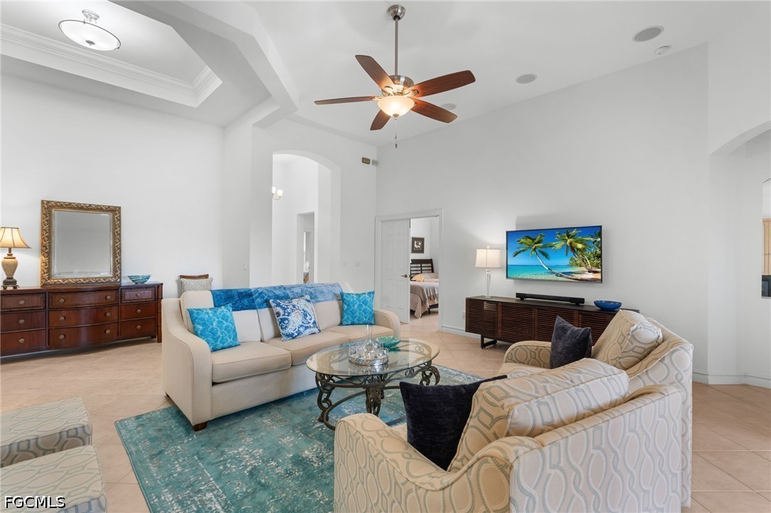 Living room with cream sofas, turquoise rug, glass coffee table, and ceiling fan.