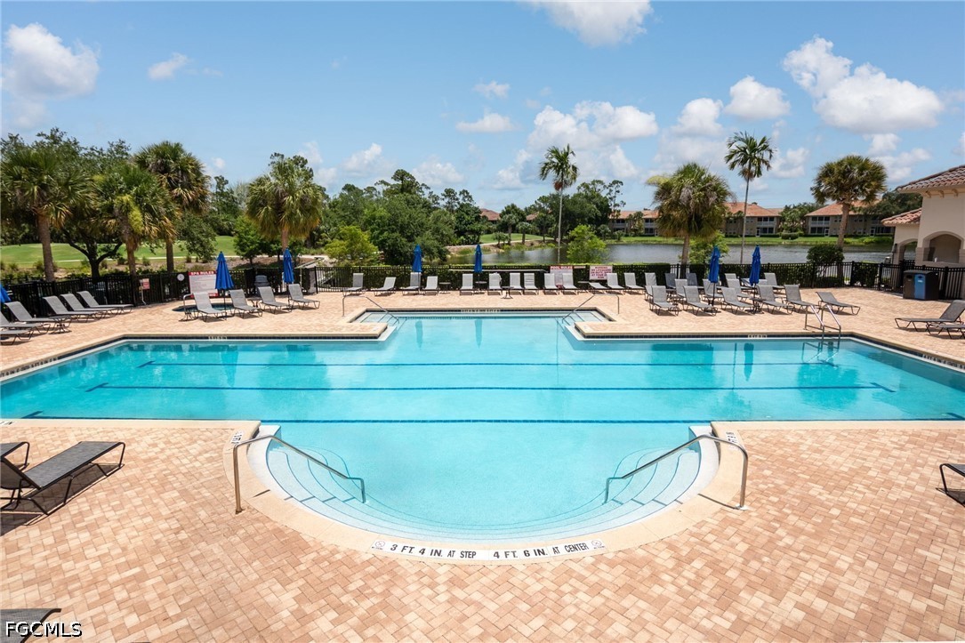 Community swimming pool with curved shallow-entry section, lounge chairs, and a pond beyond.