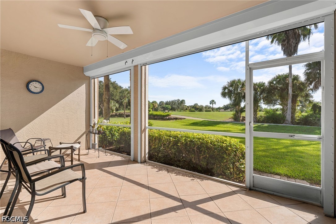Screened lanai with patio chairs overlooking a green golf course and palm trees.