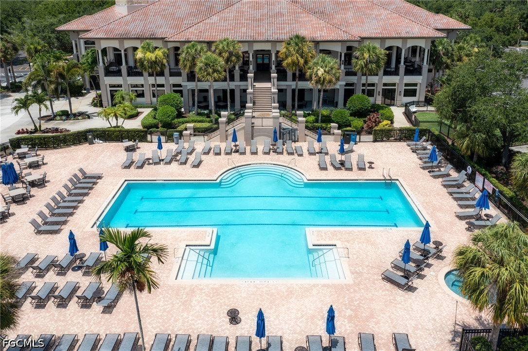 Aerial view of a community pool and clubhouse, with a broad tiled roof and rows of loungers.