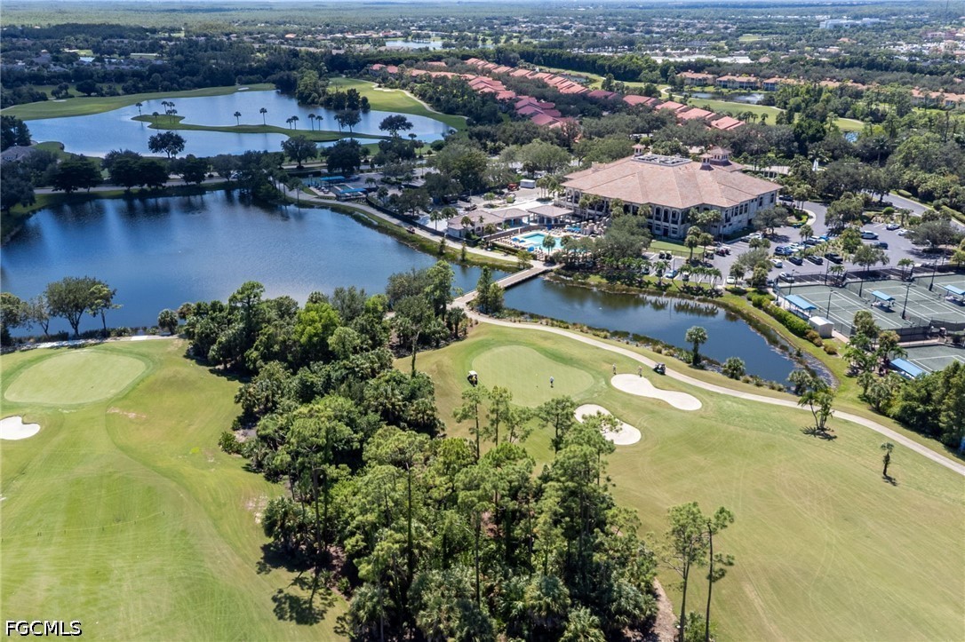 Aerial view of golf course community with lakes, clubhouse, pool, and tennis courts.