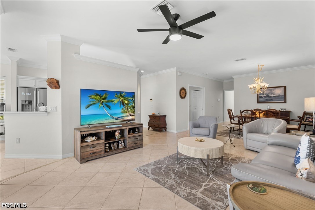 Furnished living room with gray seating, a patterned rug, ceiling fan, and dining area.