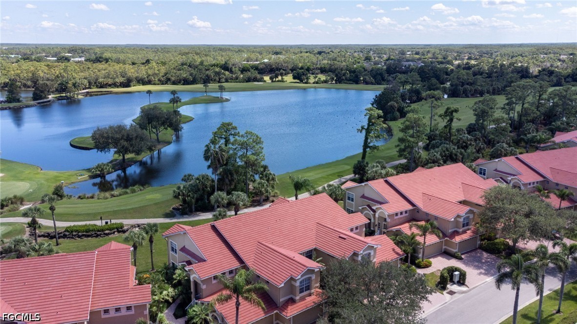 Aerial view of red tile-roof homes beside a lake and landscaped grounds.