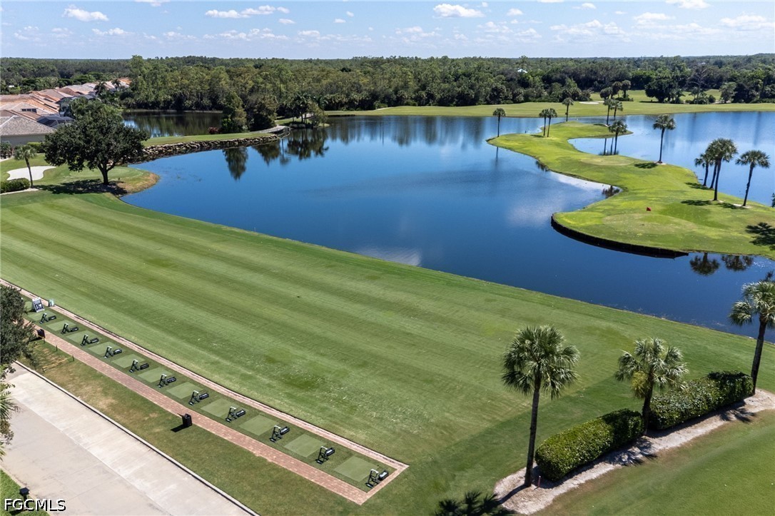 Aerial view of a golf course with a large lake, greens, and palm trees.