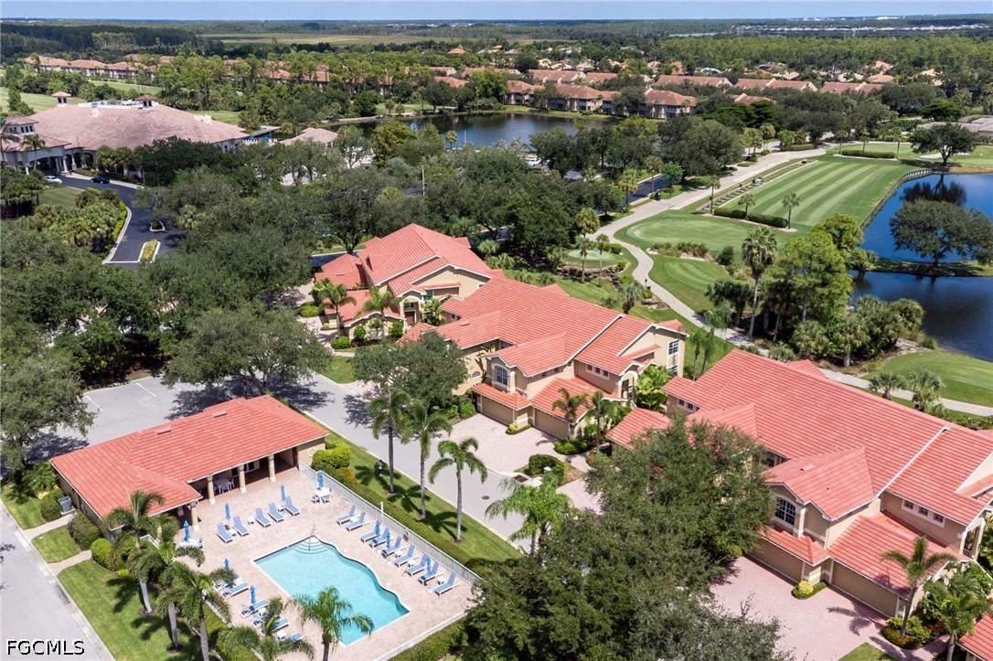 Aerial view of red-roofed homes, a community pool, and a landscaped golf course beside ponds.