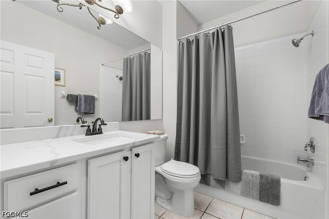 Bathroom with white vanity, large mirror, toilet, and tub behind a gray shower curtain.