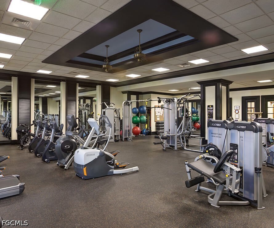 Fitness room with rows of exercise machines, mirrored walls, and a dark coffered ceiling.