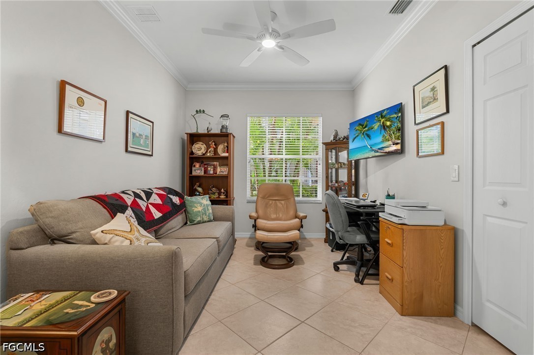 Furnished home office with a gray sofa, desk, leather recliner, and window overlooking greenery.
