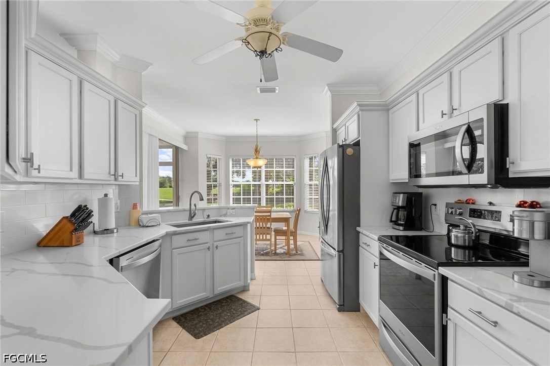 Bright white kitchen with stainless steel appliances and a breakfast nook overlooking the lawn.