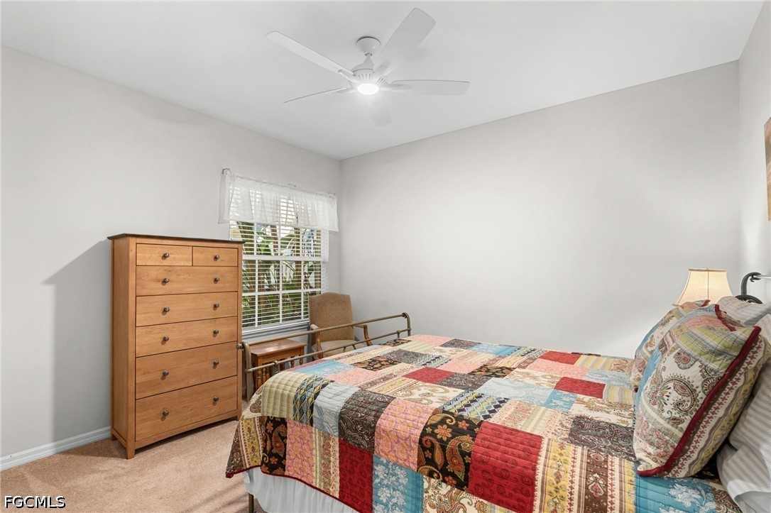Bedroom with a colorful patchwork quilt, tall wooden dresser, and ceiling fan.