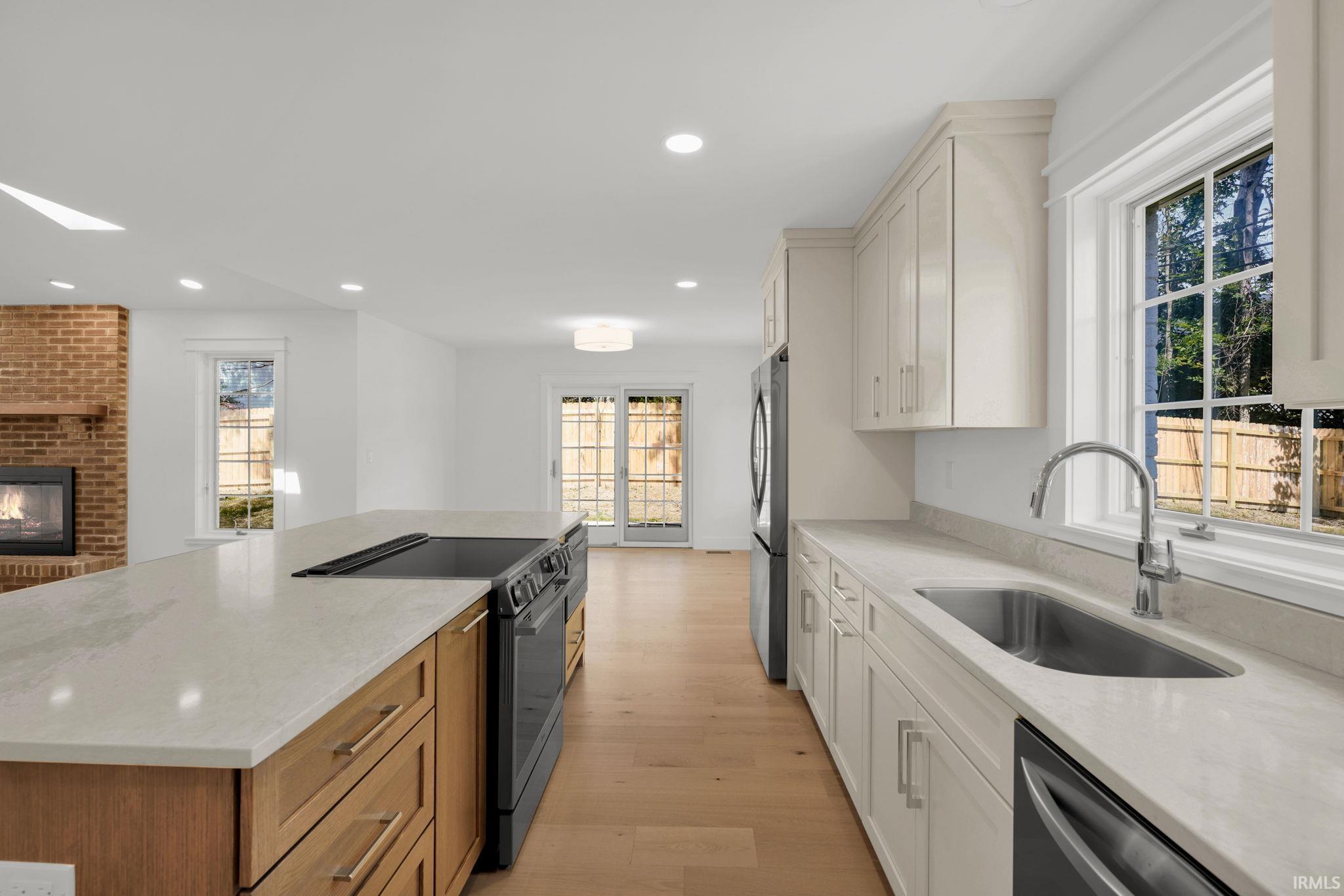 Renovated kitchen with a wood-front island, white cabinetry, and a large window over the sink.