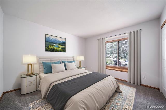 Staged bedroom with a large bed, teal pillows, matching bedside tables, and a curtained window.