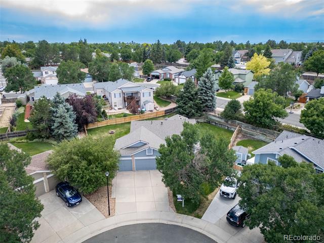 Aerial view of a suburban home with a two-car garage and curved driveway among mature trees.